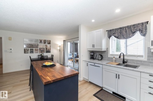 Kitchen featuring white shaker-style cabinetry, a gray subway tile backsplash, and light-toned countertops - 25 1904 Mill Woods Road Road, Edmonton, AB - Indoor Photo Showing Kitchen