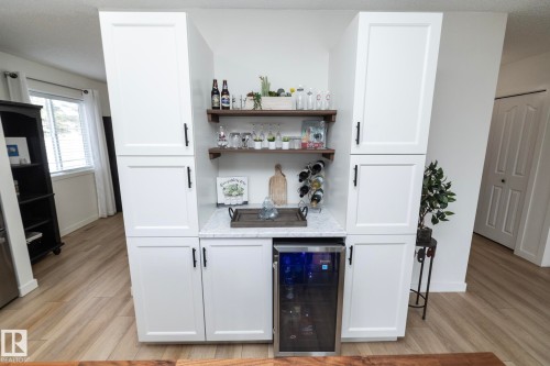 Custom built-in cabinetry featuring shaker-style doors, matte black hardware, and an integrated beverage refrigerator - 25 1904 Mill Woods Road Road, Edmonton, AB - Indoor