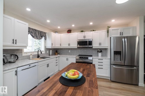 Modern kitchen with white cabinetry and stainless steel appliances - 25 1904 Mill Woods Road Road, Edmonton, AB - Indoor Photo Showing Kitchen With Upgraded Kitchen