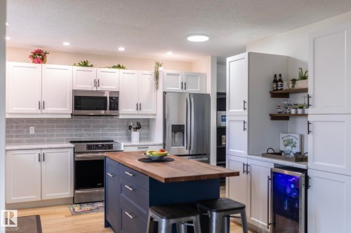 Kitchen featuring white shaker cabinetry, stainless steel appliances, a wood-top island with storage, subway tile backsplash, and recessed lighting - 25 1904 Mill Woods Road Road, Edmonton, AB - Indoor Photo Showing Kitchen With Upgraded Kitchen