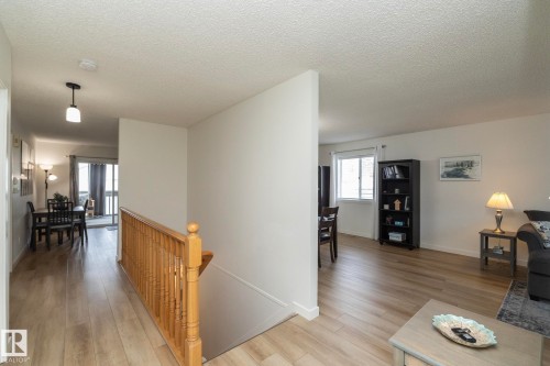 Bright interior with wood-finish flooring throughout, featuring a natural wood staircase railing and white walls - 25 1904 Mill Woods Road Road, Edmonton, AB - Indoor Photo Showing Living Room