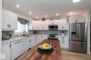 Modern kitchen featuring white shaker cabinetry, stainless steel appliances, a wood-finish island countertop, light-toned countertops, and a gray subway tile backsplash - 25 1904 Mill Woods Road Road, Edmonton, AB  - Indoor Photo Showing Kitchen With Upgraded Kitchen 