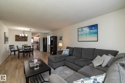 Open-concept living space with wood-finish flooring extending into the dining area - 25 1904 Mill Woods Road Road, Edmonton, AB - Indoor Photo Showing Living Room