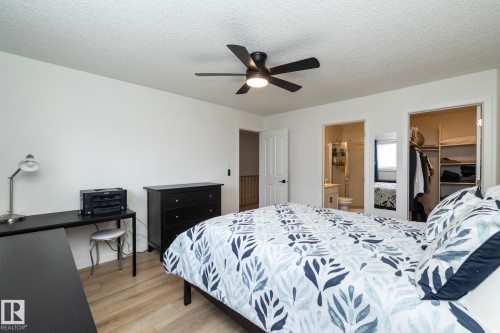 Spacious bedroom featuring wood-finish flooring, a contemporary ceiling fan, and crisp white walls - 25 1904 Mill Woods Road Road, Edmonton, AB - Indoor Photo Showing Bedroom