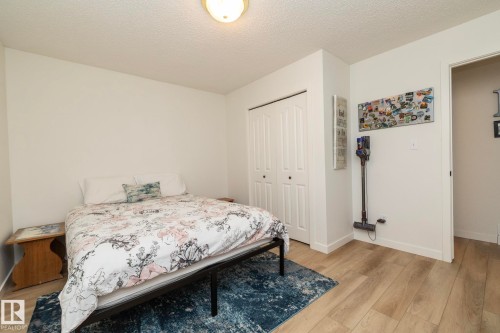 Bedroom featuring wood-finish flooring, a double-door closet, a ceiling-mounted light fixture, and white wall finishes - 25 1904 Mill Woods Road Road, Edmonton, AB - Indoor Photo Showing Bedroom