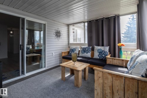 Enclosed patio featuring light gray siding, a textured ceiling, a sliding glass door, and large windows - 25 1904 Mill Woods Road Road, Edmonton, AB - Outdoor With Deck Patio Veranda With Exterior