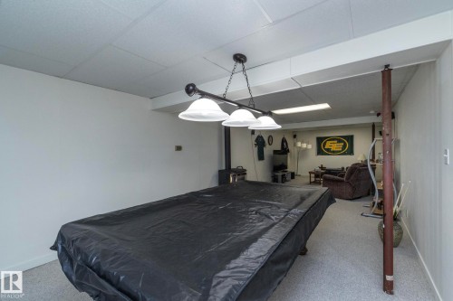 Recreation room with carpeted flooring, drop ceiling, and a multi-bulb hanging light fixture - 25 1904 Mill Woods Road Road, Edmonton, AB - Indoor Photo Showing Bedroom