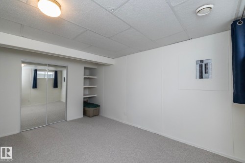 Carpeted room featuring mirrored sliding closet doors and built-in shelving - 25 1904 Mill Woods Road Road, Edmonton, AB - Indoor Photo Showing Other Room