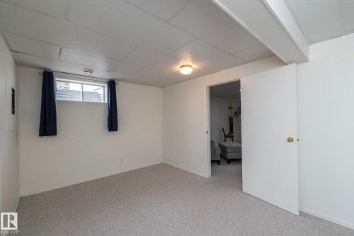 Carpeted room with white walls, drop ceiling, and exposed ceiling beams - 25 1904 Mill Woods Road Road, Edmonton, AB - Indoor