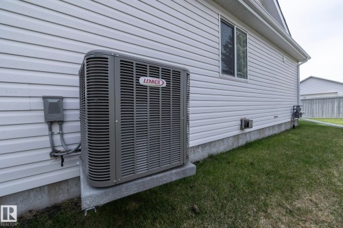 Lennox air conditioning unit on a concrete pad, situated against white vinyl siding - 25 1904 Mill Woods Road Road, Edmonton, AB - Outdoor With Exterior
