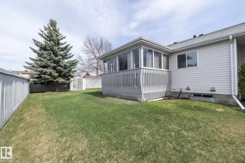 Spacious backyard featuring a sunroom, mature evergreen tree, and a storage shed - 25 1904 Mill Woods Road Road, Edmonton, AB - Outdoor