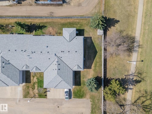 Multi-unit residential structure featuring a gray shingle roof, individual private entrances, and adjacent green space with a walking path - 25 1904 Mill Woods Road Road, Edmonton, AB - Outdoor With View