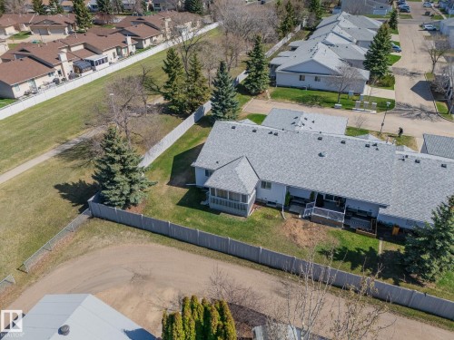 Townhome property featuring a light gray shingle roof, screened-in porch, and a rear deck with dark railings - 25 1904 Mill Woods Road Road, Edmonton, AB - Outdoor With View