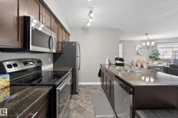 Contemporary kitchen featuring dark wood cabinetry, granite countertops, and stainless steel appliances - 