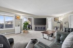 Carpeted living area featuring a large window, sliding glass door, white baseboards, and neutral wall tones - 