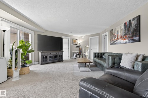 Spacious living area featuring light-toned carpet flooring, neutral wall paint, and white trim - 314 3211 James Mowatt Trail Sw, Edmonton, AB - Indoor Photo Showing Living Room