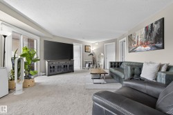 Spacious living area featuring light-toned carpet flooring, neutral wall paint, and white trim - 