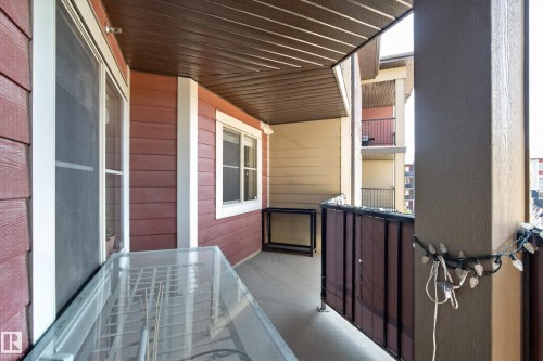 Covered balcony featuring red horizontal siding, white trim, and a textured ceiling - 314 3211 James Mowatt Trail Sw, Edmonton, AB - Outdoor With Exterior