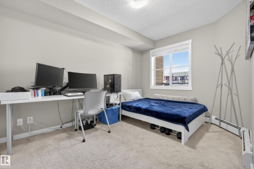 Bright room featuring a large window, neutral wall paint, and light-toned carpet flooring - 314 3211 James Mowatt Trail Sw, Edmonton, AB - Indoor Photo Showing Bedroom