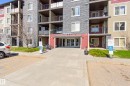 Multi-story building exterior featuring a stone facade and red accent panels, with individual balconies and ground-level patios - 314 3211 James Mowatt Trail Sw, Edmonton, AB  - Outdoor With Facade 