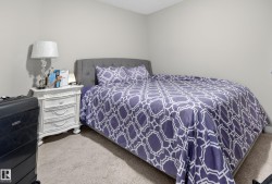 Carpeted room featuring light gray walls, a textured ceiling, and a built-in upholstered headboard - 