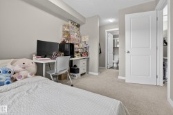 Bedroom featuring light neutral wall paint, light-colored carpet flooring, white trim, and a white two-panel interior door - 