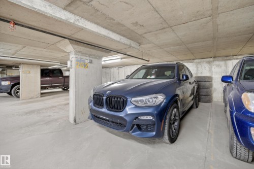 Underground parking garage featuring concrete walls and ceilings, designated parking spaces, and exposed utility piping - 314 3211 James Mowatt Trail Sw, Edmonton, AB - Indoor Photo Showing Garage