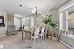 Open-concept dining area featuring a chandelier, a large window, and light-colored carpeting - 