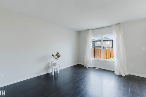 Spacious room featuring dark wood-finish flooring, white baseboards, and light neutral walls - 2082 Price Landing, Edmonton, AB - Indoor Photo Showing Other Room