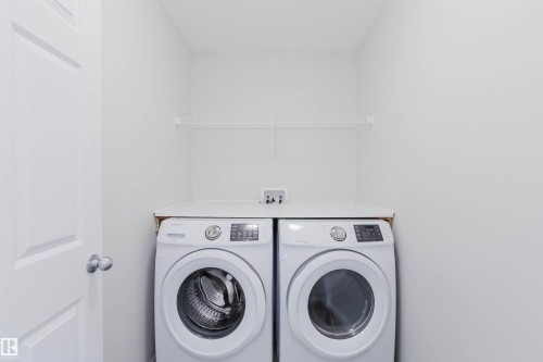 Dedicated laundry area featuring front-loading washer and dryer, white wire shelving, and a white countertop - 2082 Price Landing, Edmonton, AB - Indoor Photo Showing Laundry Room