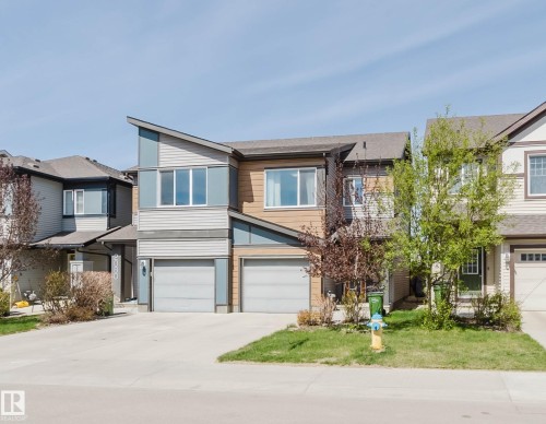 Contemporary multi-level residence featuring a unique sloped roofline, two integrated garage doors, horizontal and vertical siding, and multiple windows - 2082 Price Landing, Edmonton, AB - Outdoor With Facade