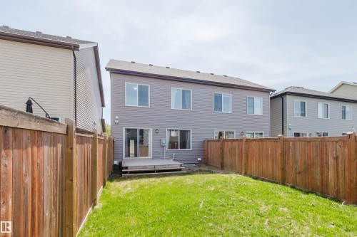 Fenced backyard featuring a wood deck, sliding glass door access, and a manicured lawn - 2082 Price Landing, Edmonton, AB - Outdoor With Exterior