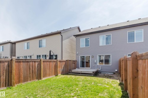Fenced backyard with a grassy lawn, featuring a wooden deck, sliding glass patio doors, and horizontal siding on the exterior - 2082 Price Landing, Edmonton, AB - Outdoor With Deck Patio Veranda With Exterior