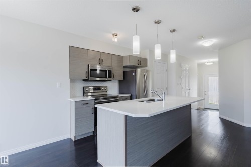 Kitchen featuring a central island with an integrated sink, white countertop, and pendant lighting - 2082 Price Landing, Edmonton, AB - Indoor Photo Showing Kitchen With Stainless Steel Kitchen With Double Sink With Upgraded Kitchen