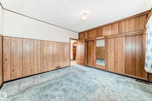 Room featuring blue-grey carpeting, wood paneling, and white upper walls - 11929 91 Street, Edmonton, AB 