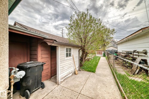 Detached garage with horizontal wood siding, a partial concrete driveway, and a concrete pathway - 11929 91 Street, Edmonton, AB 