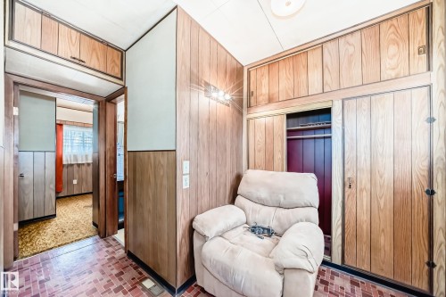 Wood-paneled room featuring built-in storage cabinetry, a recessed wardrobe with clothing rod, and a tiled floor with a geometric pattern - 11929 91 Street, Edmonton, AB 