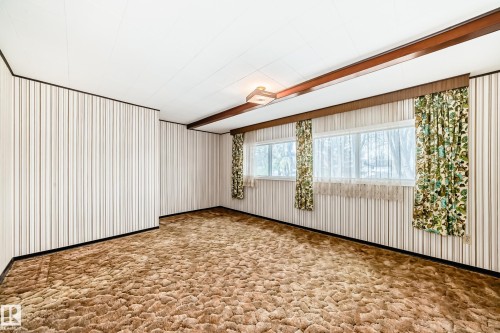 Room featuring a low-pile shag carpet, striped wall paneling, and a white acoustic tile ceiling - 11929 91 Street, Edmonton, AB 