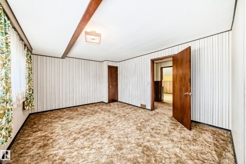 Spacious room featuring textured wall coverings, a ceiling-mounted light fixture, and two wood doors - 11929 91 Street, Edmonton, AB 