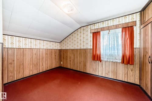 Room featuring wood paneling, patterned wallpaper, and red carpeting - 11929 91 Street, Edmonton, AB 