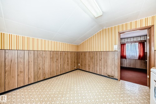 Room featuring patterned floor tile, wood-finish paneling, and striped wallpaper - 11929 91 Street, Edmonton, AB 