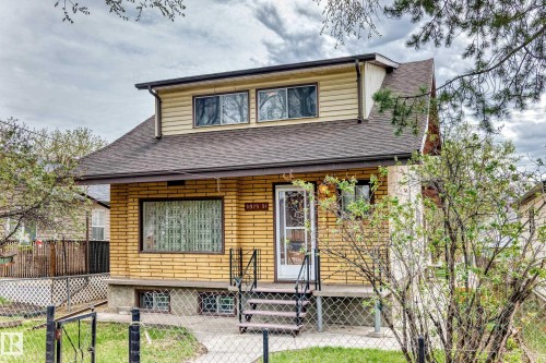 Brick exterior featuring horizontal siding on the upper level, a dark shingle roof, and a covered entry with a screen door - 11929 91 Street, Edmonton, AB 