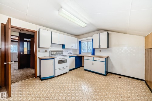Kitchen featuring white and blue cabinetry, a white electric range, a stainless steel sink, and patterned linoleum flooring - 11929 91 Street, Edmonton, AB 