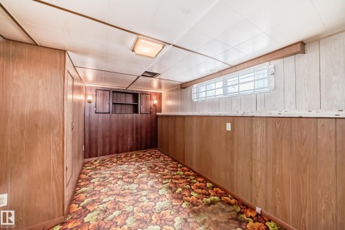 Finished room featuring wood-panel walls, built-in cabinetry, and a drop ceiling with recessed lighting - 11929 91 Street, Edmonton, AB 