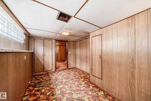 Finished room featuring wood-panel walls, patterned carpet, and a drop ceiling - 11929 91 Street, Edmonton, AB 