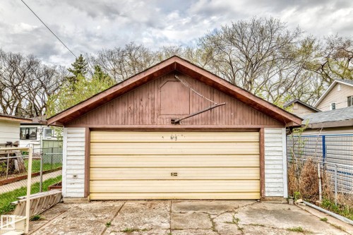 Detached garage featuring a sloped roofline, wood paneling, and a single garage door - 11929 91 Street, Edmonton, AB 