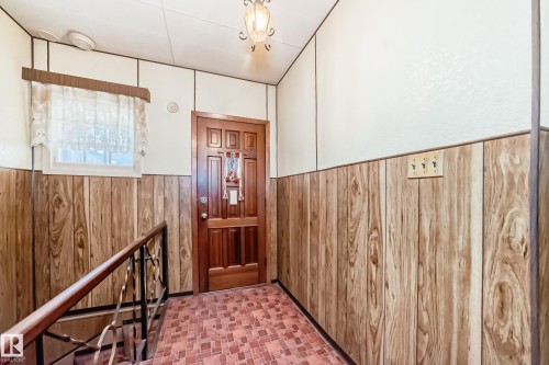 Entryway featuring wood-panel wainscoting, a paneled wood-finish door, and patterned tile flooring - 11929 91 Street, Edmonton, AB 