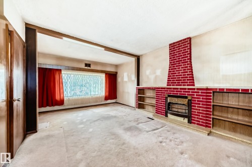 Living area featuring a floor-to-ceiling red brick fireplace with an integrated firebox, flanked by built-in shelving - 11929 91 Street, Edmonton, AB 