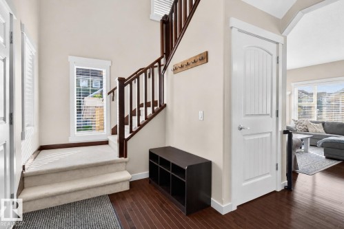 Entryway featuring rich wood-finish flooring and a carpeted staircase with dark wood railings - 8003 Summerside Grande Boulevard, Edmonton, AB - Indoor Photo Showing Other Room