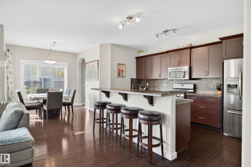 Kitchen with rich wood-finish cabinetry, stainless steel appliances, and a tiled backsplash - 8003 Summerside Grande Boulevard, Edmonton, AB - Indoor Photo Showing Kitchen